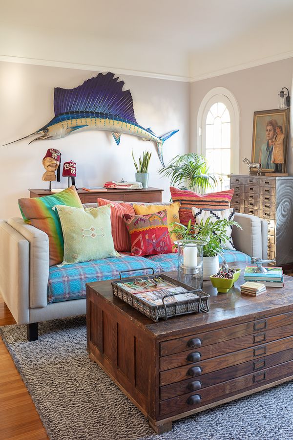Colorful pillows on modern sofa with old architect's cabinet as coffee table and 8' marlin on wall and quirky vintage accessories.