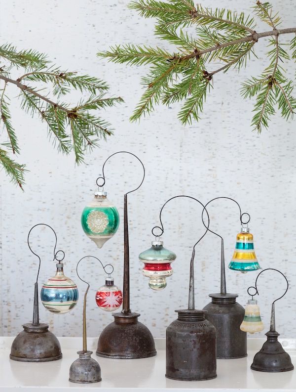 Old oil cans with wire displaying vintage ornaments.