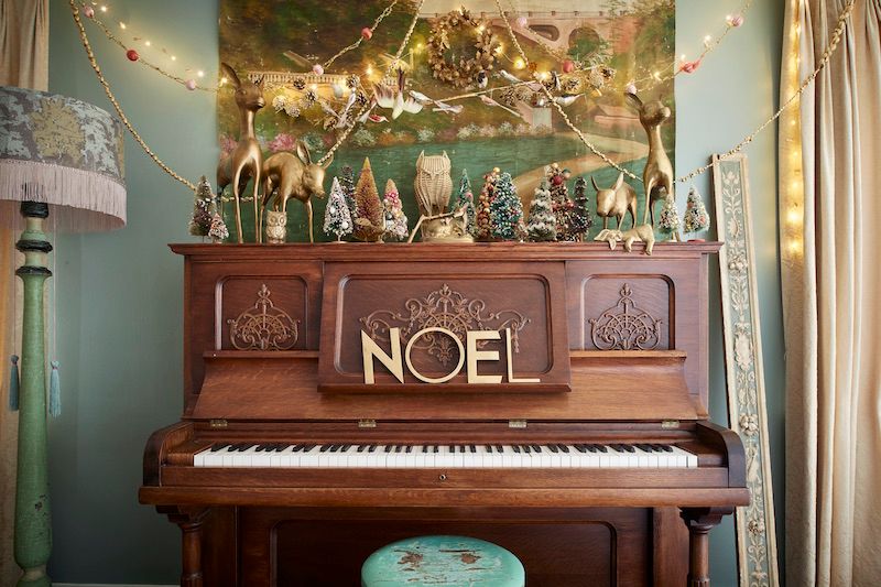 Old piano with vintage bottle brush Christmas trees and brass deer vignette.