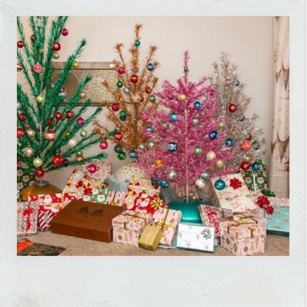 Assortment of brightly colored vintage aluminum trees with gifts underneath.
