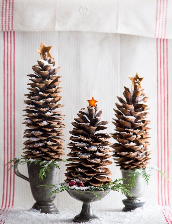 Supersized pinecones standing upright in pewter vessels as holiday decor.