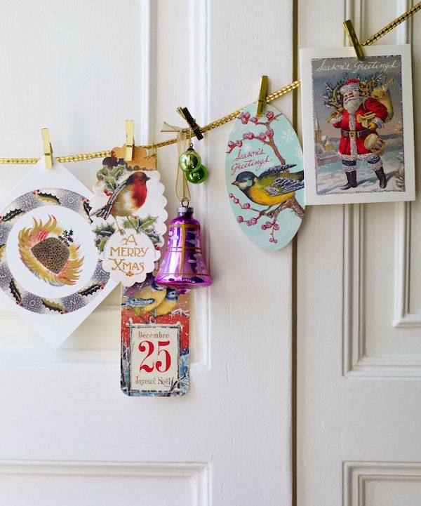 Vintage gold trim displaying cards using small clothespins and ornaments threaded with ribbon.