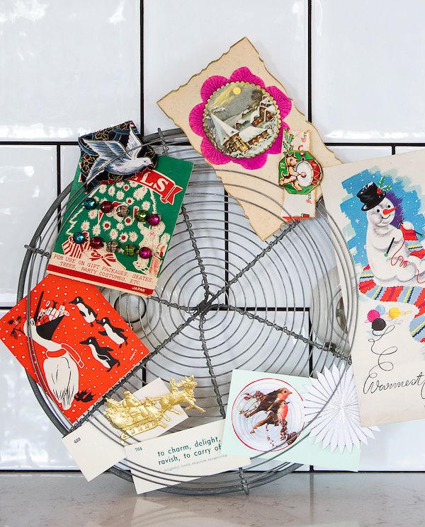 A vintage cake cooling rack serving as a wreath form with cards and other ephemera slipped along the outside edges.