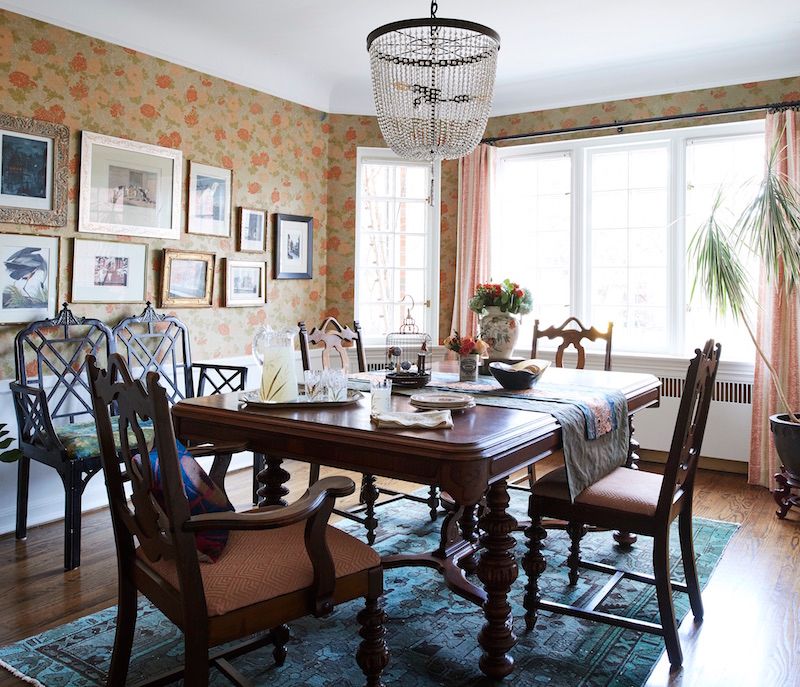 Formal dining room with crystal chandelier, floral wallpaper and gallery art wall. Also an antique dining table.