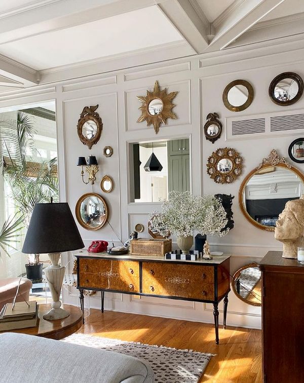 Living room with console and wall filled with vintage mirrors.