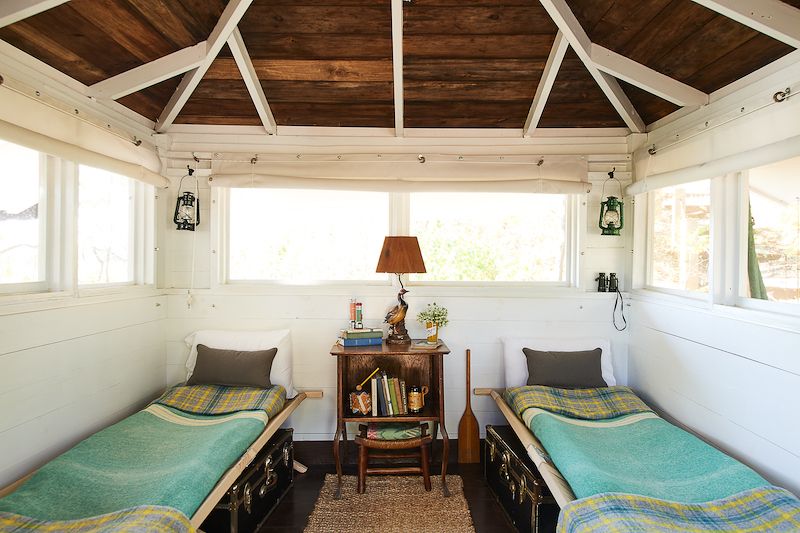 Vintage cots in bedroom of small cabin.