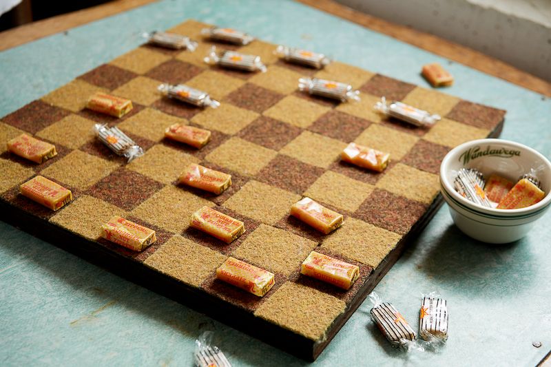 Retro candies used as game pieces on an old checkerboard.