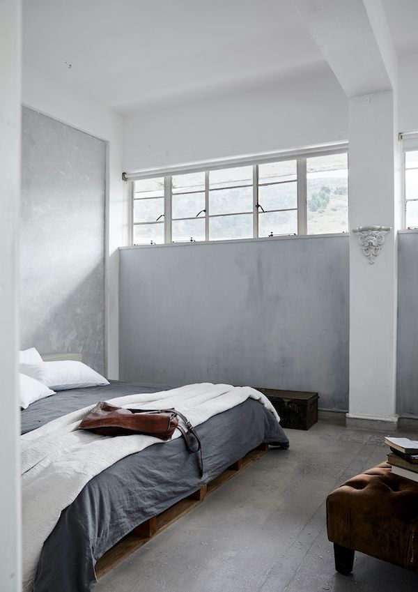 Simple bedroom with white and light gray walls and minimal vintage furniture.