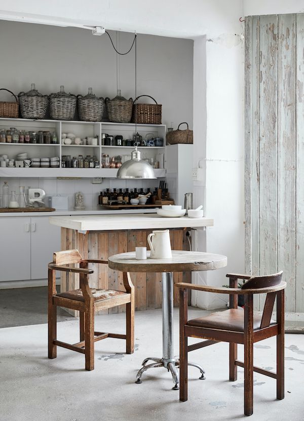 Vintage style kitchen with open white shelving and rustic wood table.