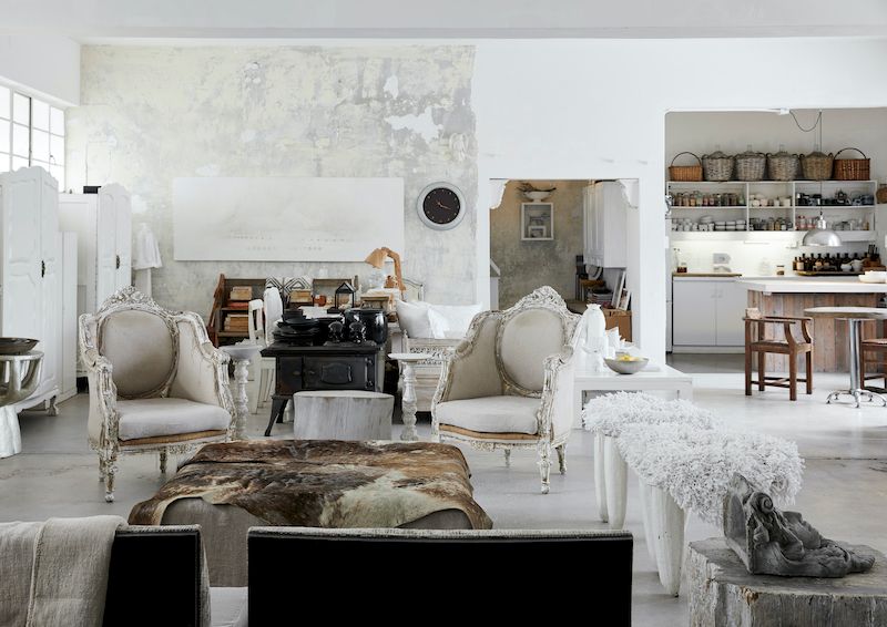 Open floorpan living space with white rustic walls and neutral vintage furniture and accessories.