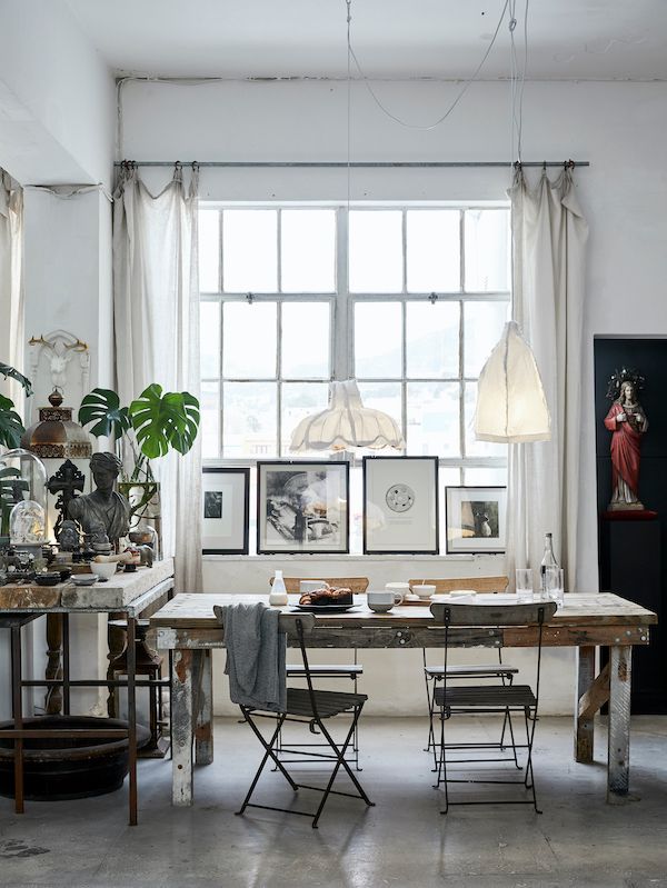 Rustic furniture and vintage accessories in dining area with large bright windows.