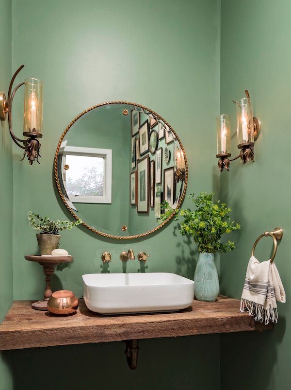 Salvaged barn wood used as countertop in bathroom with green walls and vintage accessories.