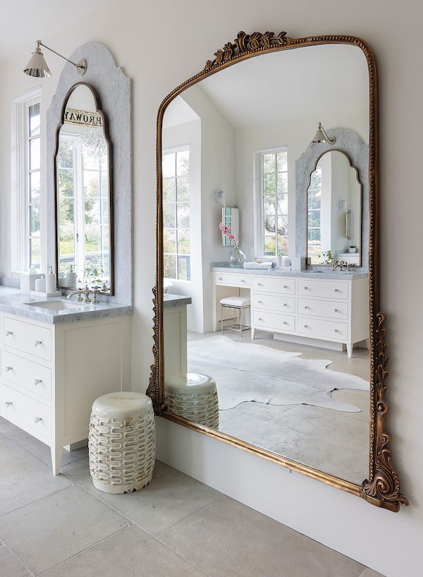 White walls in bathroom with large vintage brass mirror.