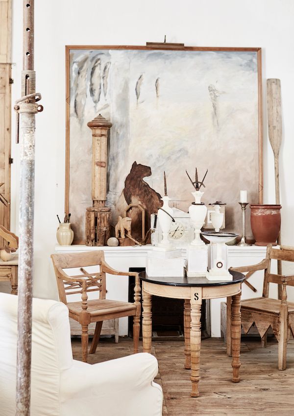 Studio with vintage furniture and accessories including urns and a large painting.